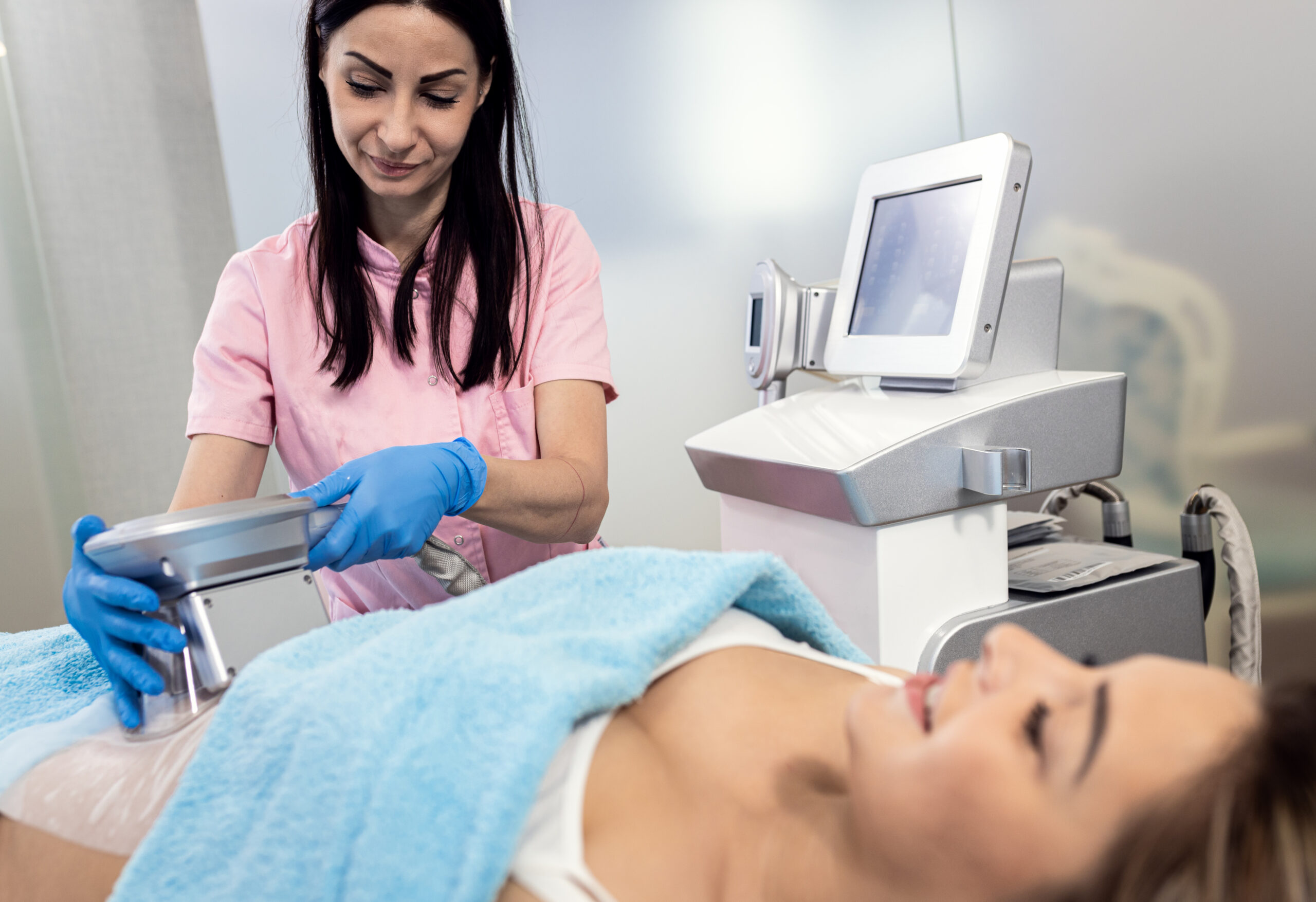Beautician therapist applying cryolipolysis treatment in beauty salon.